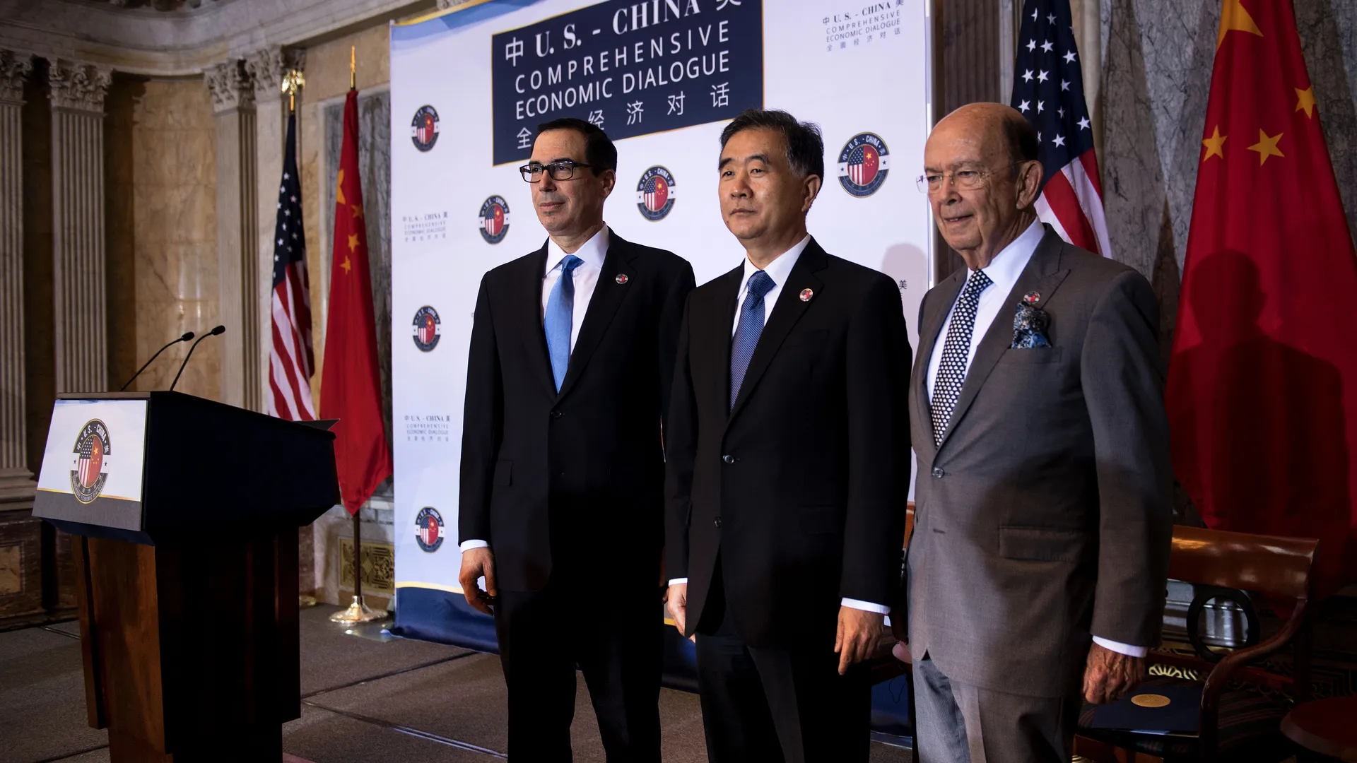 Officials at a podium in front of a branded &lsquo;U.S.–China Comprehensive Economic Dialogue&rsquo; backdrop, flanked by U.S. and Chinese flags.
